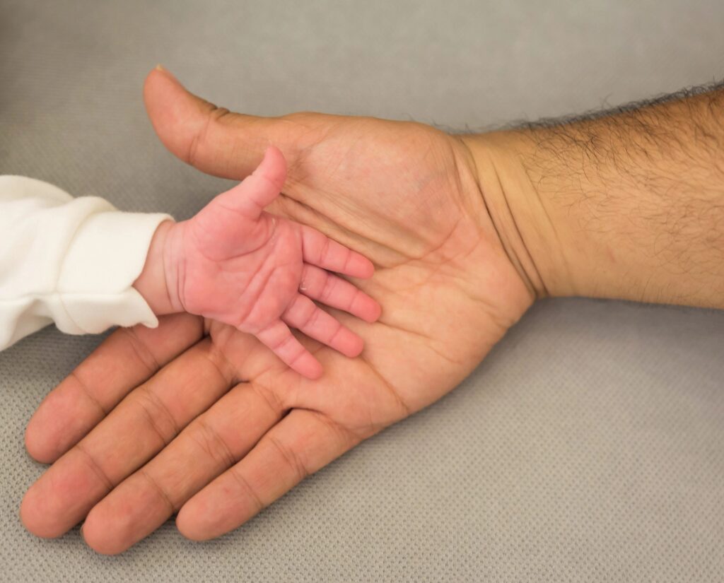 Father's hand holding his newborn son hand