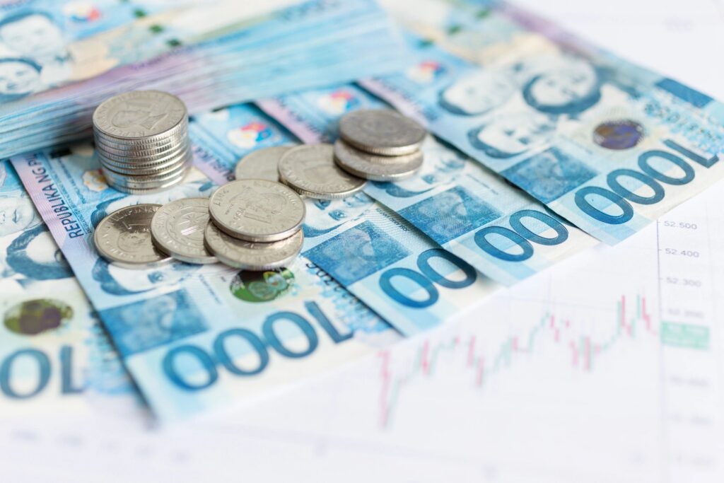 Close up of cash banknote of one thousand Philippines peso and coins with paper graphs diagrams, macro