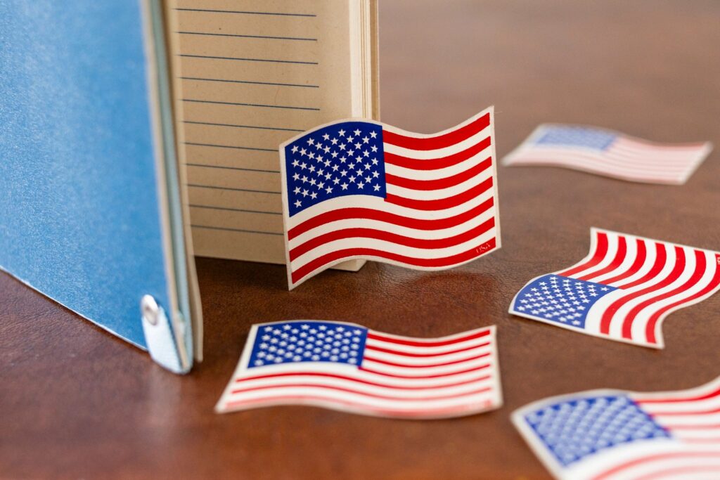 A collection of small USA flags represented as stickers placed near a notebook